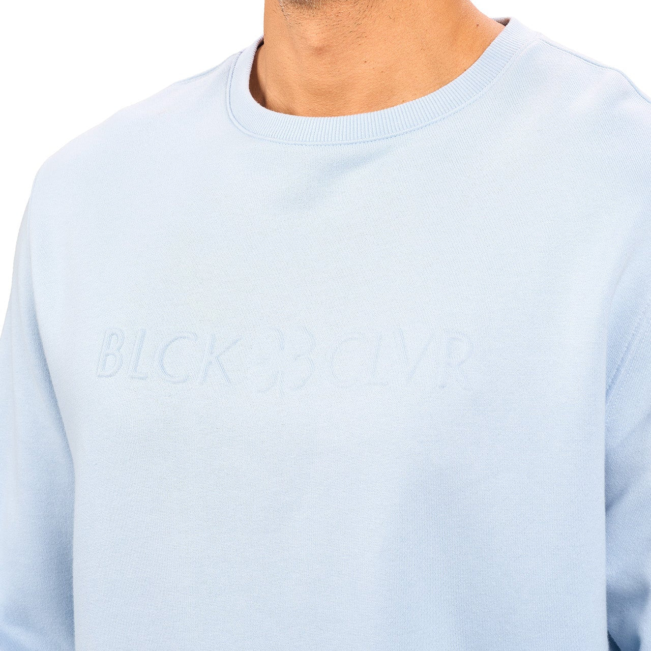 man wearing an light blue colored sweater from Black Clover with a 3d text BLCK CLVR on the chest