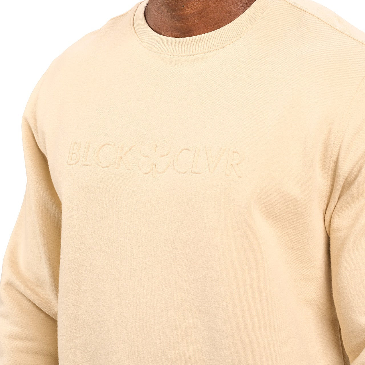 man wearing an oatmeal colored sweater from Black Clover with a 3d text BLCK CLVR on the chest